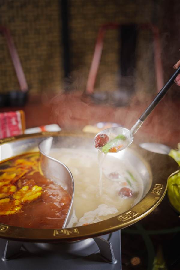 Ladle lifting from a steaming split hotpot, 8Treasures