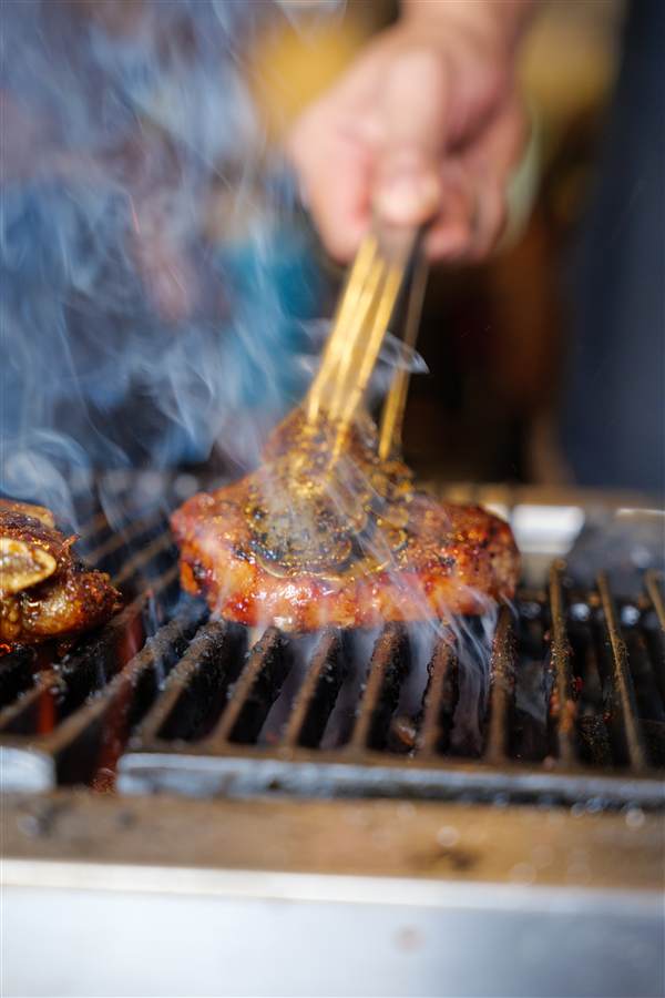 Meat patty basted on a smoking charcoal grill, Soto Afung