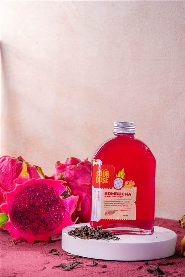 Red kombucha bottle with dragon fruit on a pink set, Sourdose