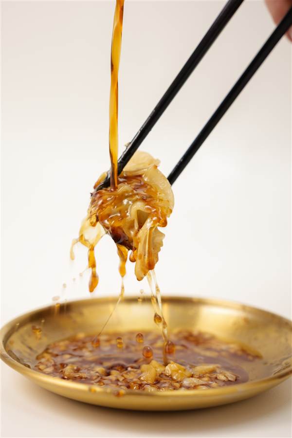 Noodles lifted with chopsticks over a gold plate, Tianbanana